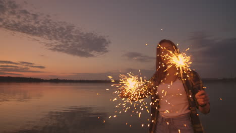 Dancing-friends-with-fireworks-have-fun-and-celebrate-the-holiday-together-guys-and-girls-in-the-summer-on-the-beach.-Sparklers-in-the-hands-of-people-having-fun.