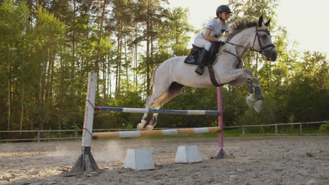 The-women-demonstrates-skills-in-jumping-with-a-horse-over-an-obstacle-in-a-horseclub.