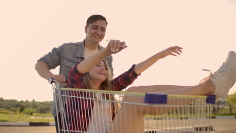 Young-friends-having-fun-on-shopping-trolleys.-Multiethnic-young-people-racing-on-shopping-cart.-slow-motion