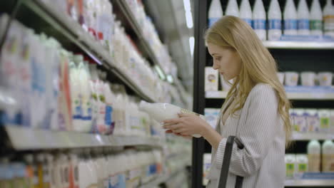 Werbung-Für-Ein-Lebensmittelgesundheitskonzept---Eine-Frau-Steht-In-Einem-Supermarkt-Vor-Dem-Gefrierschrank-Und-Entscheidet-Sich,-Eine-Flasche-Frische-Milch-Zu-Kaufen.-Milch-Trinken-Für-Die-Gesundheit.
