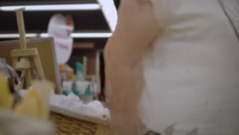 Attractive-girl-customer-is-buying-bread-in-bakery-department-is-shop-smelling-it-smiling-and-putting-in-shopping-trolley.-Healthy-lifestyle-and-supermarket-concept.