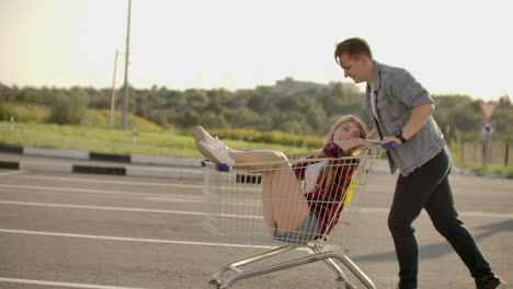 Slow-motion:-a-Free-and-cheerful-man-and-woman-ride-in-carts-in-a-supermarket-Parking-lot-shouting-and-raising-their-hands-in-the-air