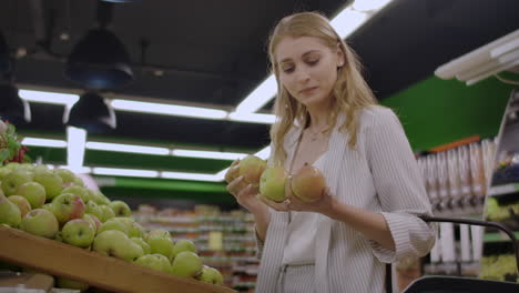 Una-Joven-Atractiva-Eligiendo-Manzana-En-El-Mercado-De-Supermercados-De-Frutas-Y-Verduras
