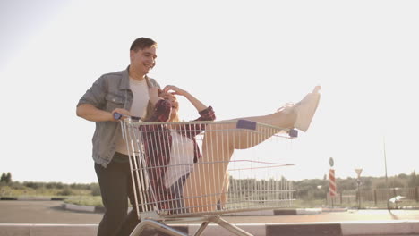 A-man-runs-and-pushes-a-supermarket-cart-rolling-a-girl-in-it-crazy-fun-of-students