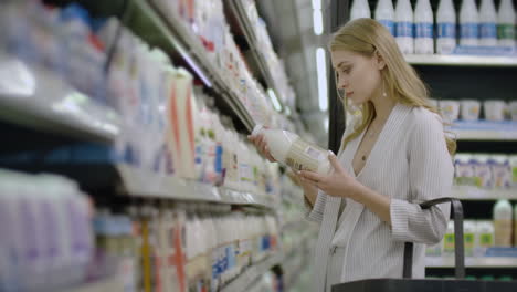 Werbung-Für-Ein-Lebensmittelgesundheitskonzept---Eine-Frau-Steht-In-Einem-Supermarkt-Vor-Dem-Gefrierschrank-Und-Entscheidet-Sich,-Eine-Flasche-Frische-Milch-Zu-Kaufen.-Milch-Trinken-Für-Die-Gesundheit.