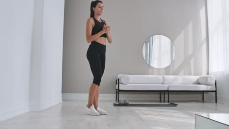 Cheerful-sportive-woman-doing-side-lunges.-Middle-aged-happy-sportswoman-living-room-doing-side-lunges-and-smiling-forward-while-training