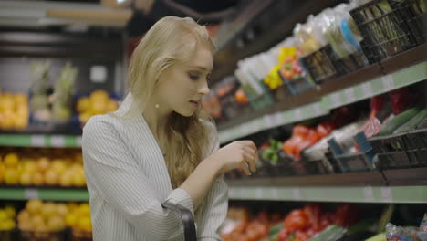 Young-beautiful-brunette-girl-in-her-20's-picking-out-napa-cabbage-and-cauliflower-and-putting-them-into-shopping-cart-at-the-fruit-and-vegetable-aisle-in-a-grocery-store