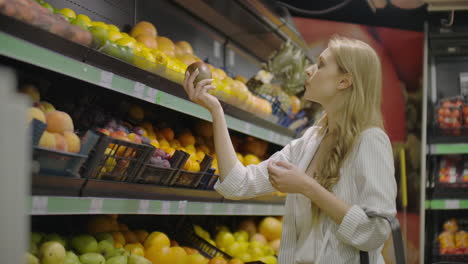 Young-Woman-Choosing-Ripe-Mangoes-in-Grocery-Store.-Vegan-Zero-Waste-Girl-Buying-Fruits-and-Veggies-in-Organic-Supermarket-and-Using-Reusable-Produce-Bag.-4K-Slowmotion