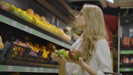 Young-Woman-Choosing-Ripe-Mangoes-in-Grocery-Store.-Vegan-Zero-Waste-Girl-Buying-Fruits-and-Veggies-in-Organic-Supermarket-and-Using-Reusable-Produce-Bag.-4K-Slowmotion