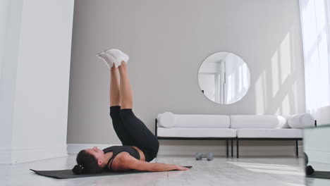 Strength-training-body-weight-workout-woman-athlete-doing-Flutter-Kicks.-European-female-adult-doing-floor-exercises-with-Leg-Raises-to-exercise-abs-muscles-at-home-in-his-apartment