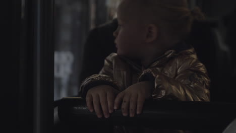 A-baby-girl-in-a-golden-jacket-sitting-in-the-bus-on-mothers-lap