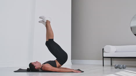 Strength-training-body-weight-workout-woman-athlete-doing-Flutter-Kicks.-European-female-adult-doing-floor-exercises-with-Leg-Raises-to-exercise-abs-muscles-at-home-in-his-apartment
