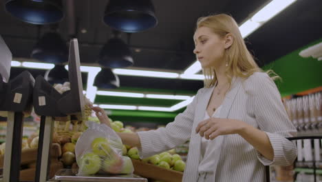 Middle-aged-woman-weighs-a-bag-of-apples-in-the-supermarket