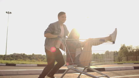 A-man-runs-and-pushes-a-supermarket-cart-rolling-a-girl-in-it-crazy-fun-of-students