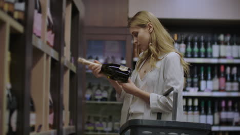 Woman-chooses-wine-in-the-Supermarket-customer-selects-product-on-the-shelves-in-the-store-in.-Alcohol-sale.-Read-the-label-on-the-wine-bottle.