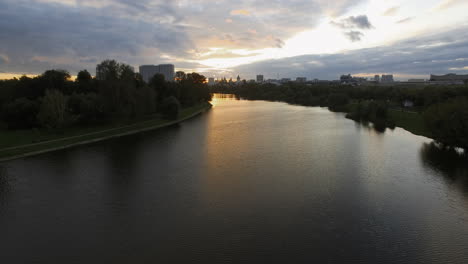 An-aerial-evening-view-of-a-wide-river-surrounded-by-dark-tree-crowns