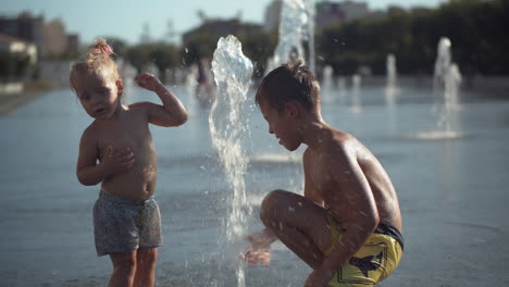 Siblings-play-with-a-fountain