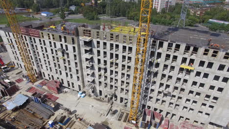 Unfinished-apartment-complex-with-builders-on-the-top-aerial