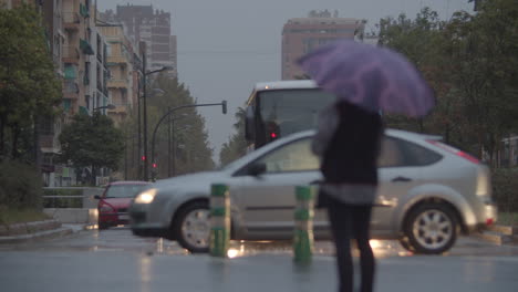 Nasty-rainy-evening-Street-view-with-traffic-and-woman-under-umbrella