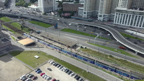 An-aerial-view-of-a-busy-highway-next-to-the-railway-station-and-urban-buildings