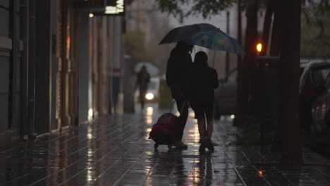 Mom-and-son-walking-in-the-street-under-the-rain