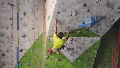 Young-Woman-Rock-climber-is-Climbing-At-Inside-climbing-Gym.-slim-pretty-Woman-Exercising-At-Indoor-Climbing-Gym-Wall