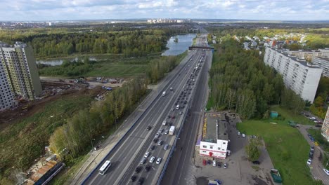 An-aerial-view-of-an-endless-highway-with-busy-traffic-in-the-middle-of-the-green-urban-scenery