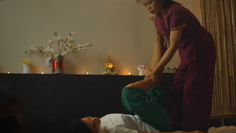 Young-woman-lying-down-while-enjoying-the-acupressure-techniques-of-traditional-Thai-massage-at-luxury-spa-and-wellness-center
