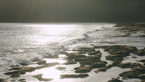 Lanzarote-Küste-Mit-Meereswellen,-Die-Vulkanische-Steine-Im-Sonnenlicht-Umspülen