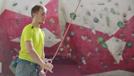 Close-up-of-Climber-man-belaying-another-climber-against-a-wall-with-hooks-in-slow-motion