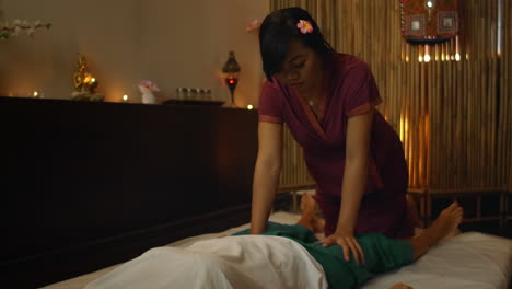 Asiatische-Frau-Führt-Bei-Schöner-Europäischer-Frau-Eine-Traditionelle-Thai-Massage-Durch.-Rehabilitation-Und-Behandlung-Nach-Verletzungen-Mit-Hilfe-Einer-Massage.-Entspannen-Und-Erholen-Sie-Sich-Von-Der-Massage-Der-Beine,-Arme-Und-Des-Rückens.-Therapeutische-Massage