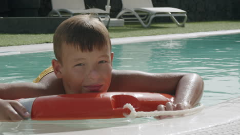 Heute-Ist-Er-Zu-Faul-Zum-Schwimmen,-Entspannter-Junge,-Der-Auf-Einem-Sicherheitsring-Im-Pool-Schwimmt