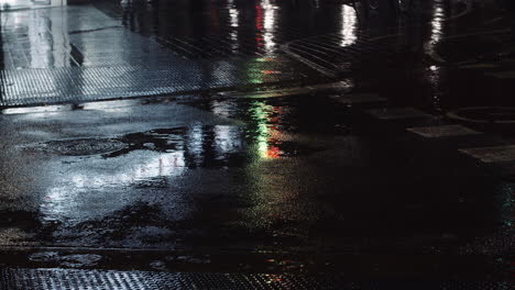 Nieselregen,-Pfützen-Und-Nächtliche-Stadtlichter,-Die-Sich-Auf-Der-Straße-Spiegeln