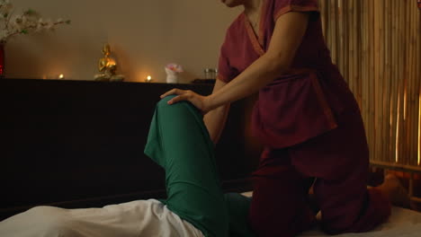 Asian-Woman-performs-Traditional-Thai-Massage-to-beautiful-European-Woman.-Rehabilitation-and-Treatment-after-Injuries-with-the-help-of-Massage.-Relax-and-Rest-from-massage-of-Legs-Arms-and-Back.-Therapeutic-massage