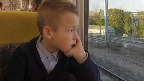 Boy-looking-through-train-window-trying-to-distract-from-thoughts