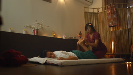 Young-woman-lying-down-while-enjoying-the-acupressure-techniques-of-traditional-Thai-massage-at-luxury-spa-and-wellness-center