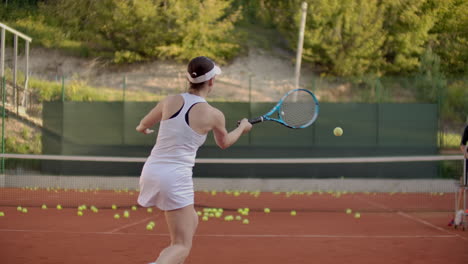 Woman-tennis-player-practicing-hitting-the-ball-with-the-coach-hitting-the-ball-with-a-racket-in-slow-motion.-Professional-tennis-player-training.