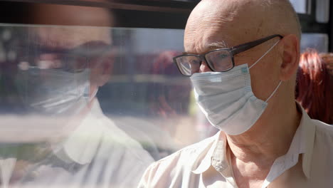 Senior-man-wearing-mask-to-prevent-COVID-19-infection-during-bus-ride