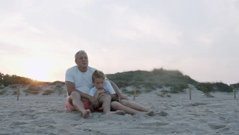 Grandfather-and-grandson-are-sitting-in-the-dunes