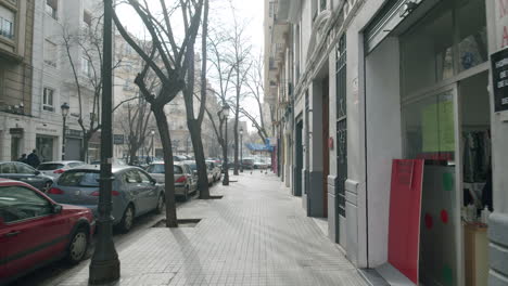 Leere-Straße-Mit-Geparkten-Autos-Und-Schaufenstern-Im-Sonnigen-Morgen-In-Valencia