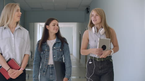 University-corridors-three-girls-go-along-the-corridor-and-laugh-cheerfully-and-talk-about-school-and-guys.-College-Institute-and-Communication