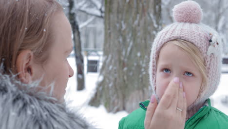 Mutter-Trägt-Am-Wintertag-Feuchtigkeitscreme-Auf-Das-Gesicht-Ihrer-Tochter-Auf