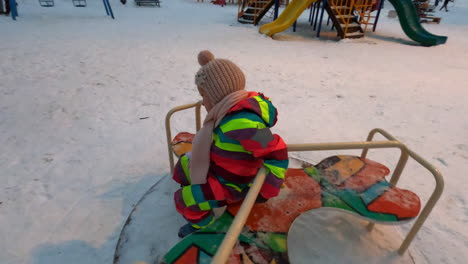 Cheerful-kid-on-playground-spinner-in-winter