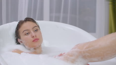 A-beautiful-brunette-woman-lies-in-a-bubble-bath-and-rests-from-a-working-day.