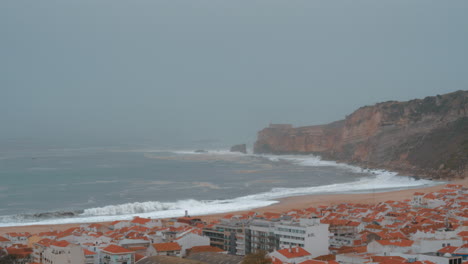 Nazare-coast-scene-with-oceanfront-hotels-and-lighthouse-on-the-rock-Portugal