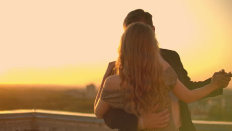 A-man-and-a-woman-in-love-dance-standing-on-the-roof-of-a-building-at-sunset-looking-at-each-other.