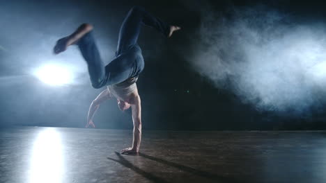 Modernes-Ballett:-Ein-Mann-Macht-Aus-Sitzender-Position-Auf-Der-Bühne-Einen-Rückwärtssalto-Mit-Drehung-Auf-Einer-Dunklen-Bühne-Im-Rauch-Im-Scheinwerferlicht.