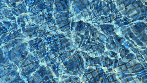 Wavy-water-in-the-swimming-pool-blue-tile-and-sunlight-glistening