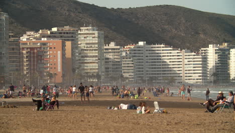 Crowded-ocean-beach-with-hotel-building-seaside-resort