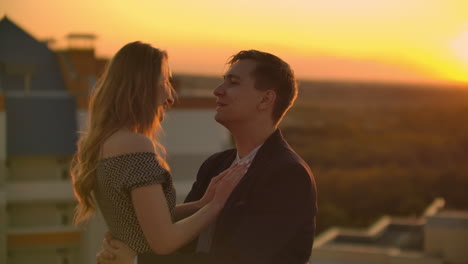 Lovely-sweet-happines-couple-sit-on-the-roof-top-with-amazing-sunset-view-on-the-urban-city-town.-They-love-each-other-hugs-very-tenderness-sun-goes-between-hair